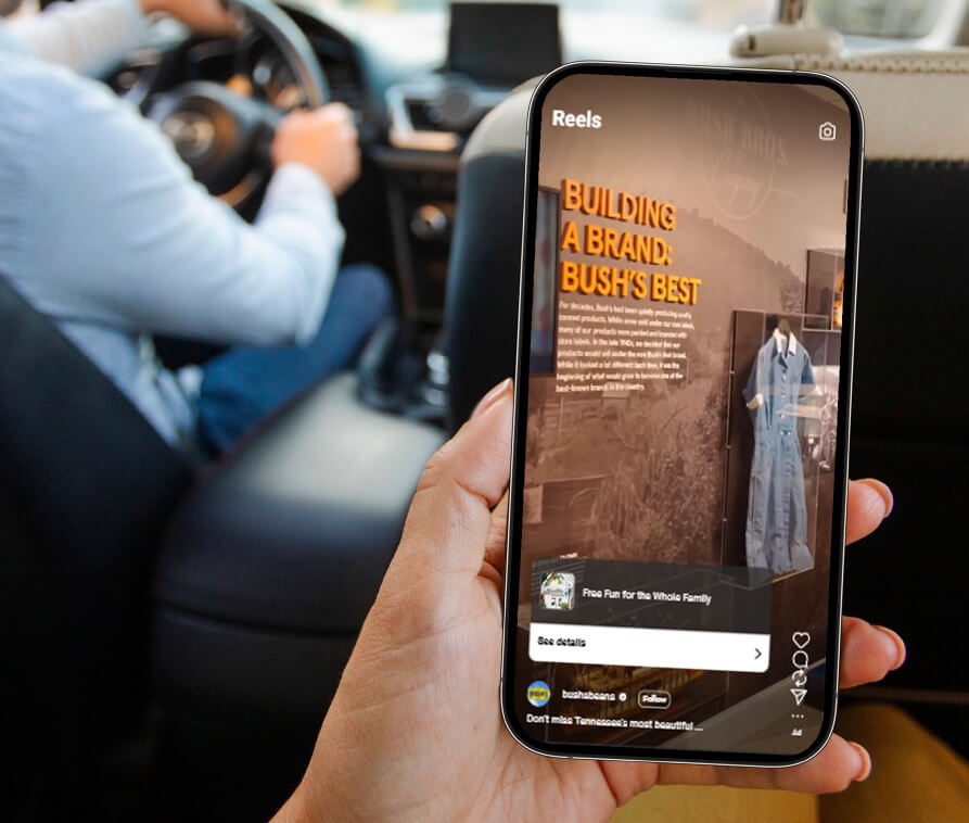 Person looking at Bush's content on phone, while riding in backseat of vehicle