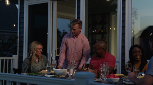 Man bringing dinner food out to family on patio