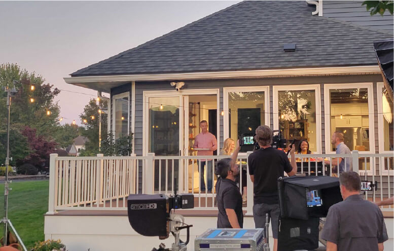 Behind the scenes filming of man bringing dinner food out to family on patio